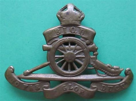 A Royal Artillery Other Ranks Cap Badge Numbered In Helmet And Cap Badges