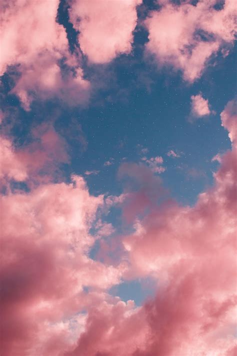 There Is A Kite Flying High In The Sky With Pink Clouds And Blue Sky