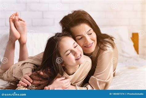 Happy Young Mother And Her Daughter Hugging On Bed At Home Panorama