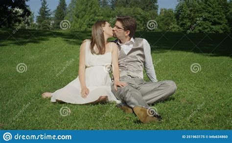 Beautiful Devoted Couple Sit On The Ground In Green Park Playfully Kissing Stock Image Image