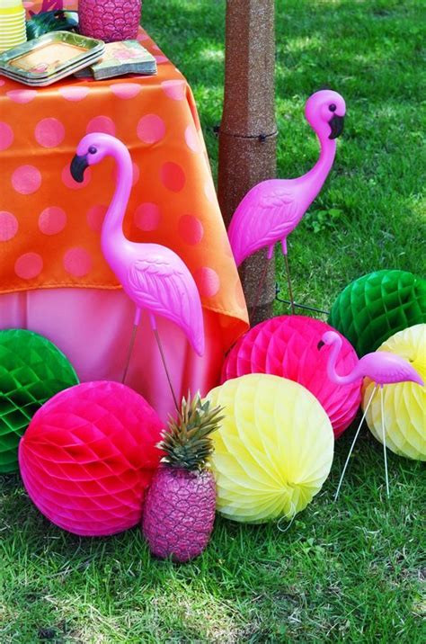 Pink Flamingos And Pineapples Are Sitting On The Grass Next To Paper Balls
