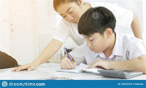 Asian Mother Helping Her Son Doing Homework On White Table Stock Image