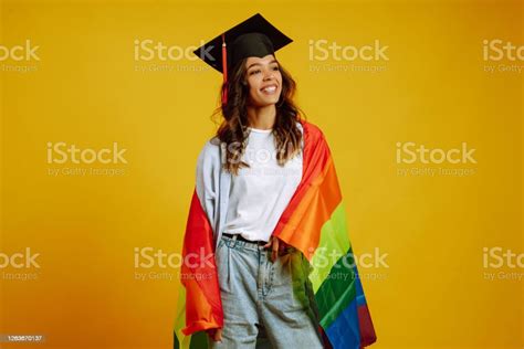 beautiful african american lesbian girl in a graduation hat posing with lgbt rainbow flag on a