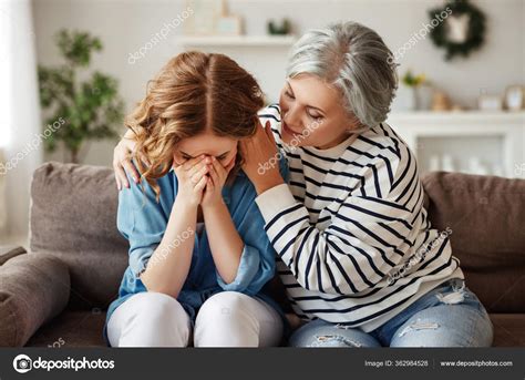 Elderly Woman Embracing Supporting Crying Young Daughter While Sitting