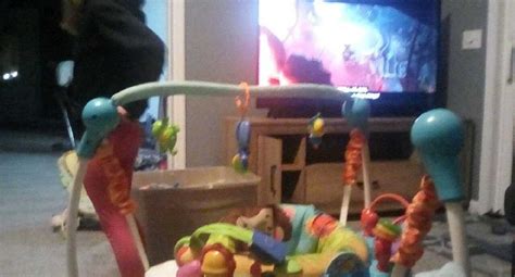 A Baby Swing In Front Of A Tv With Toys On The Floor Next To It