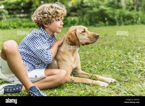 Portrait Of Boy Sitting Petting Dog In Garden Stock Photo Alamy