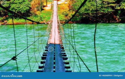 Vibrant View Of Old Rope Wooden Bridge Hanging Over Wild Cold River In