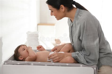 Mother Changing Baby S Diaper On Bed At Home Closeup Stock Photo