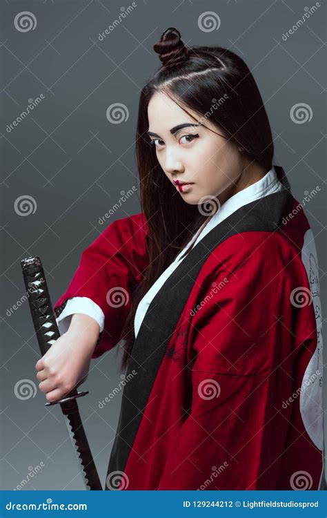 Young Asian Woman In Kimono Holding Katana And Looking At Camera Stock