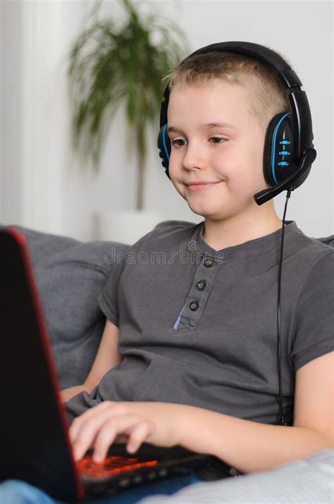 Happy Boy In Headphones Playing Online Video Game On Laptop Computer At
