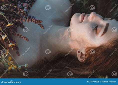 Close Up Face Of Beautiful Girl Lying On The Grass With Bouquet Of