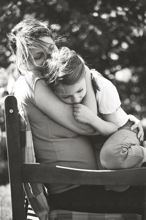 mother cuddling and hugging her daughter black and white shot by stocksy contributor lea