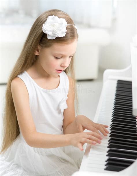 Portrait Of Little Child In White Dress Playing Piano Stock Image