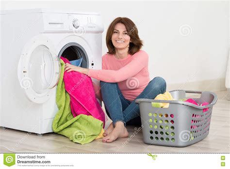 Happy Woman Putting Clothes Into Washing Machine Stock