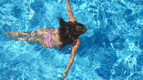 Unrecognizable Beautiful Girl Floating Across The Pool Of Hotel Young