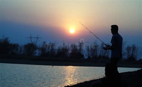 People Fishing On The Shores Of The Lake With A Sunset View Stock Image