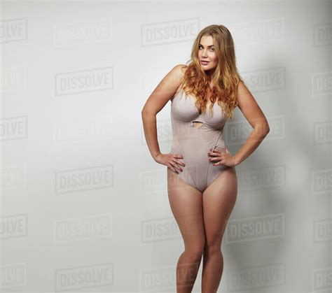 Chubby Young Woman In Body Stockings Standing On Grey Background With