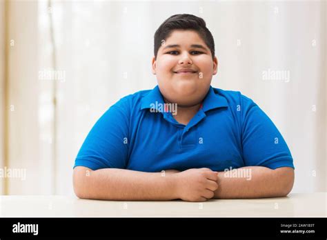 Portrait Of A Chubby Boy Sitting With His Hands On The Table Obesity