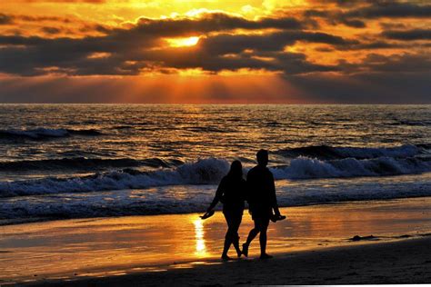 A Couple Walks On The Beach At Sunset In Oceanside August 11 2013 By