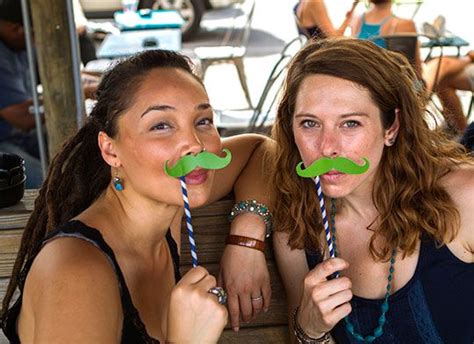 Two Women With Fake Moustaches On Their Mouths Are Posing For The Camera