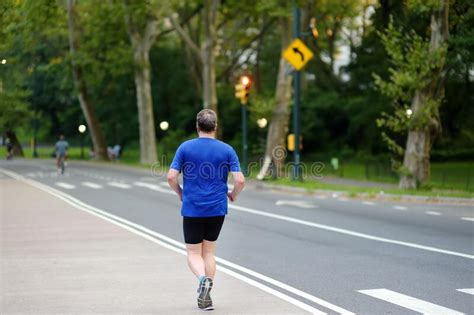 Middle Age Man Jogging In Central Park Of New York In Summer Evening