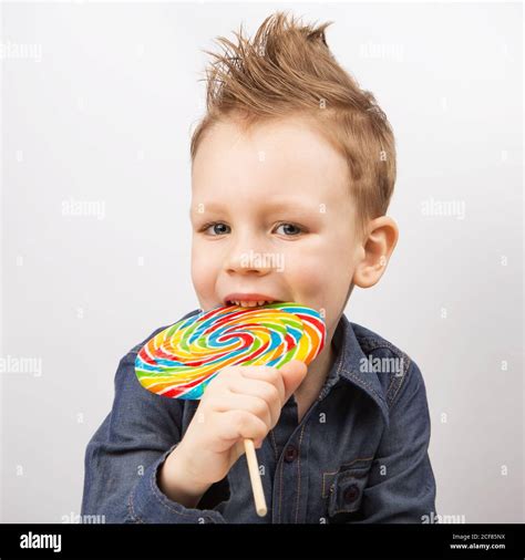 A Boy In A Denim Shirt Eating Lollipop Happy Kid With A Big Candy
