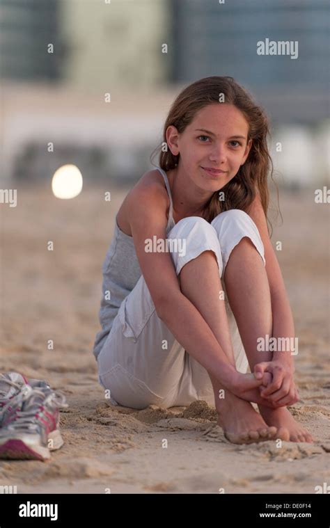 Preteen Girl Sitting On Beach With Barefeet Hugging Knees Stock Photo