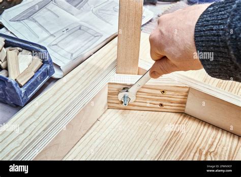 Skilled Craftsman Twists Screw On Joint Gusset Of Table Of Plywood