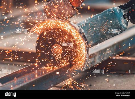 Construction Worker Using Angle Grinder Cutting Metal At Construction
