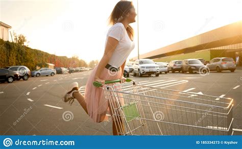 Happy Young Girl In Pink Skirt Riding On Shopping Cart At Mall Car Parking Stock Image Image