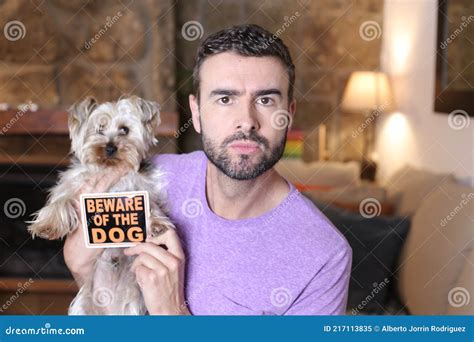 Man Holding Beware Of The Dog Sign Holding Tiny Yorkshire Terrier Stock
