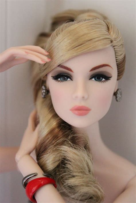 A Close Up Of A Doll With Blonde Hair And Red Bracelets On Its Wrist