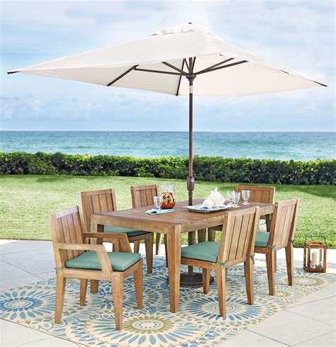 An Outdoor Dining Table Set With Chairs And An Umbrella Over It On A