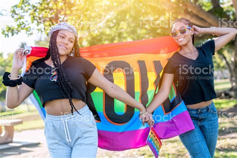 African American Young Lesbians Holding A Rainbow Banner With The Word