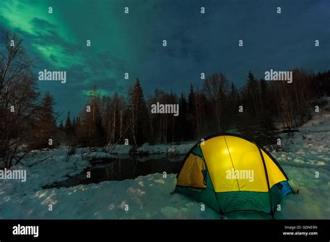 Aurora Borealis Northern Lights Above Tent Lit Up With Lantern Near