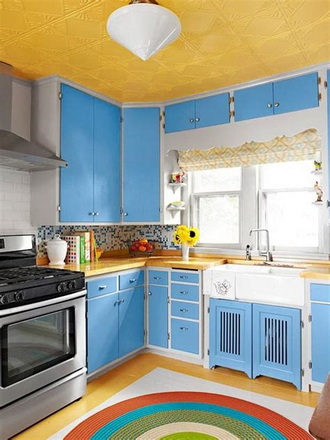 Blue backsplash tiles add a nice accent to the yellow cabinetry and white appliances in this kitchen with open shelving and natural hardwood flooring. Photos of blue and yellow kitchens