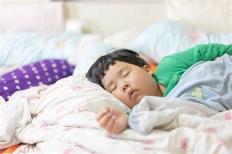 A Sleepy Child Is Sleeping On The Comfortable Bed Stock Photo Image