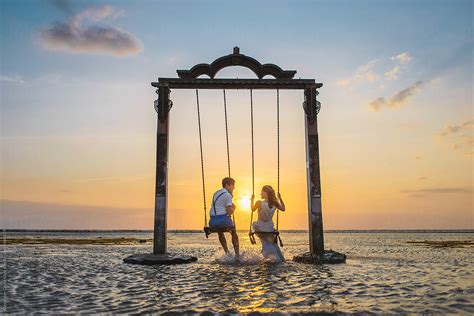 Couple On A Swing At Sunset Beach By Stocksy Contributor Alexander Grabchilev Stocksy