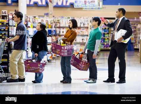 People Waiting In Line With Shopping Baskets At Grocery Store Stock