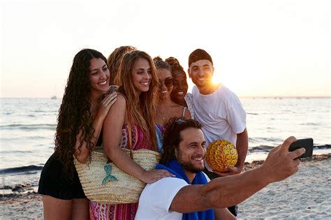 Friends Taking Selfies On A Beach At Dusk By Stocksy Contributor Ivan Gener Stocksy