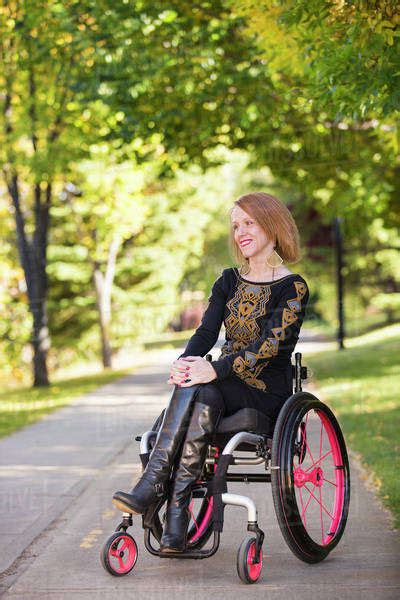 Young Paraplegic Woman In Her Wheelchair On A Path In A City Park In