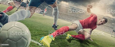 Soccer Player In Sliding Tackle During Football Match In Stadium Stock