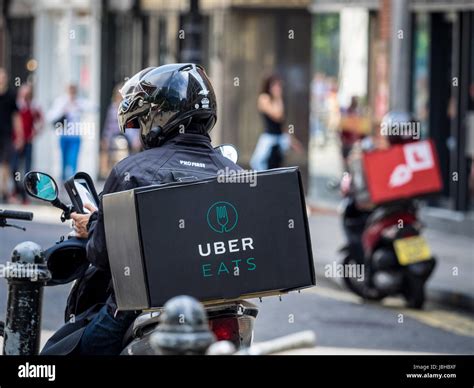 An Uber Eats food delivery courier waits for work in Central London ...