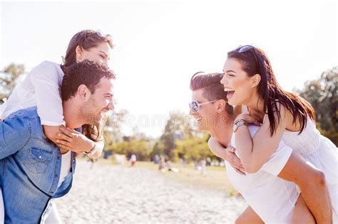Group Of Young Happy People Carrying Women On A Sandy Beach Stock Photo