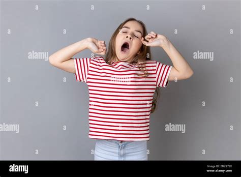 Portrait Of Sleepy Little Girl Wearing Striped T Shirt Yawning And