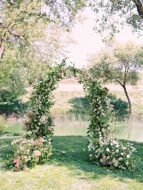 An Outdoor Ceremony Setup With Flowers And Greenery On The Grass