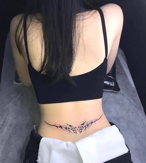 The Back Of A Woman S Stomach With An Arrow Tattoo On Her Left Side