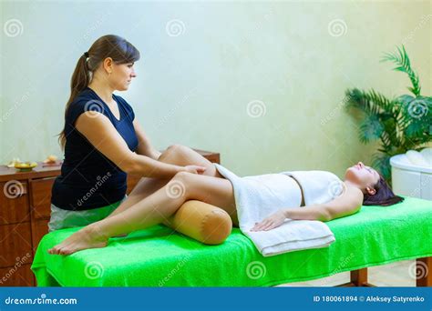 Front View Of Professional Massage Therapist Giving Massage On Woman Legs In The Spa Salon Stock
