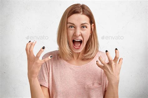 Mad Irritated Young Woman Screams Loudly And Gestures Actively Being