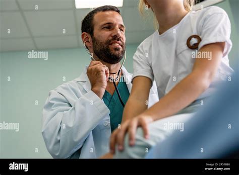Doctor Giving Checkup With Stethoscope To Young Girl In Exam Room Stock